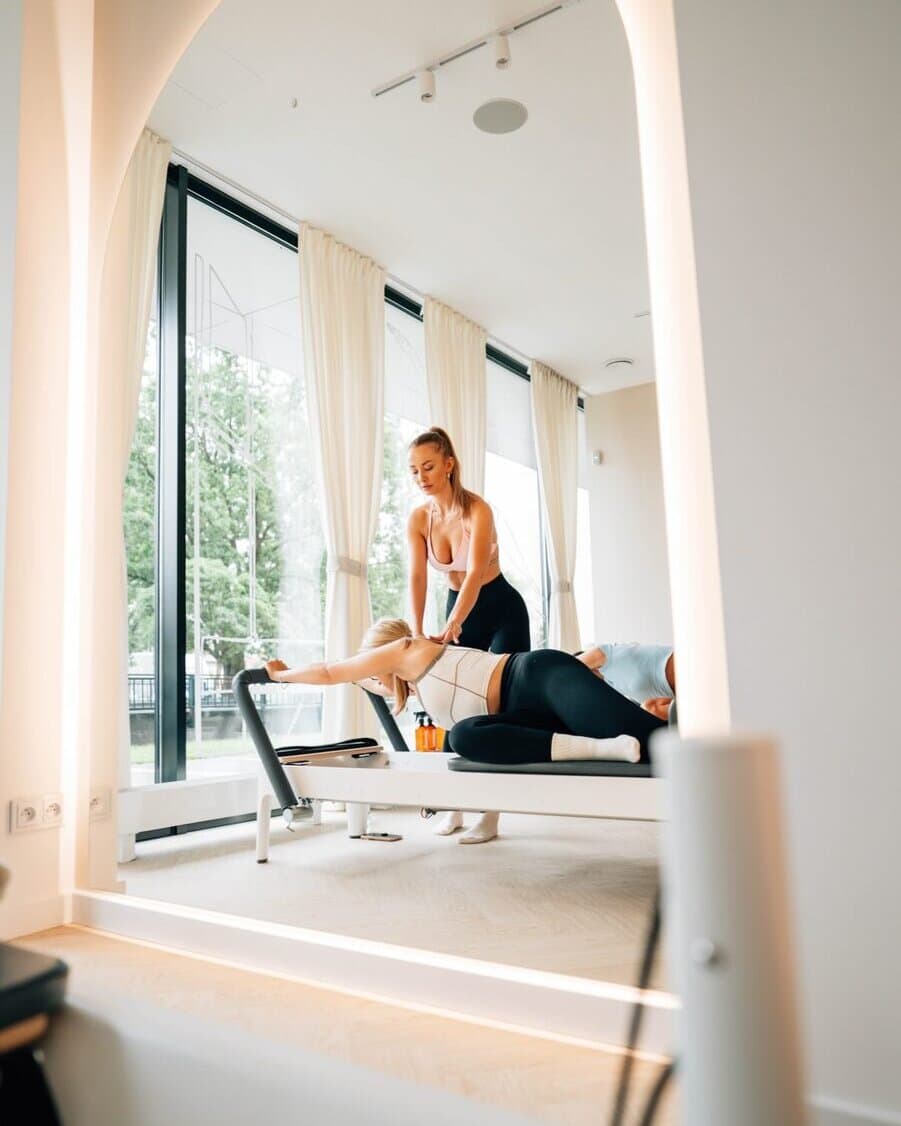 Instruktorka pilates koryguje pozycję klientki na reformerze